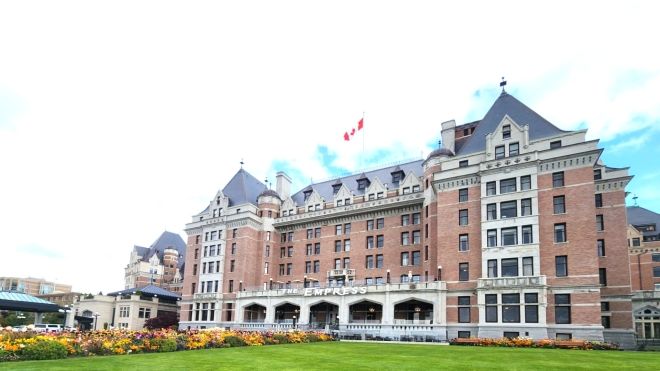 Exterior view of the Fairmont Empress Hotel with gardens and a lawn in the foreground.