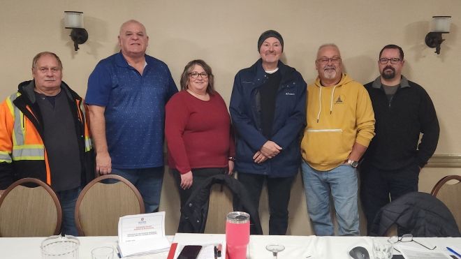 Six people standing behind a table.