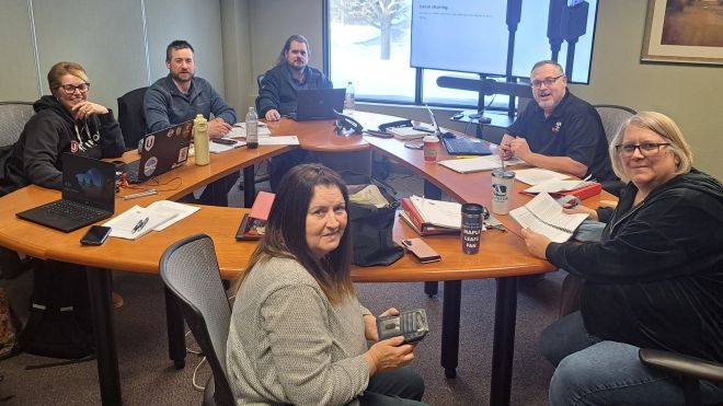 A group of six people sitting around a round table smiling at the camera