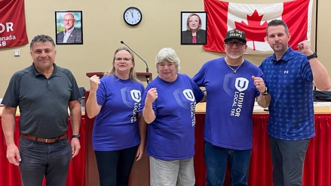 Five people posing the a Unifor and Canadian flag in the background