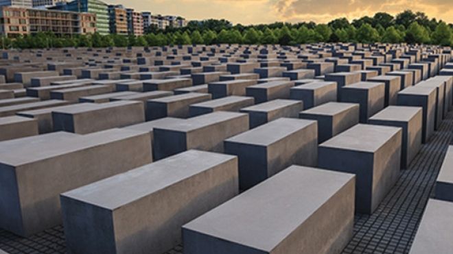 Large rectangular stone blocks are lined up into the distance at a Holocaust memorial in Berlin.	