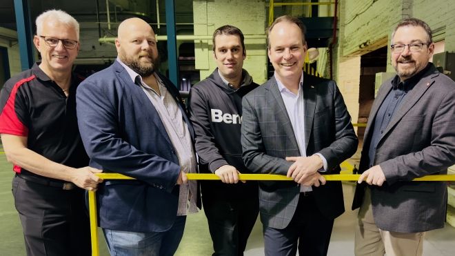cinq hommes dans une usine près d'une balustrade jaune 