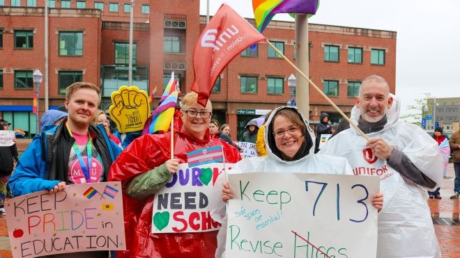 Unifor members hold signs at a rally against a review of NB Policy 713 in Moncton