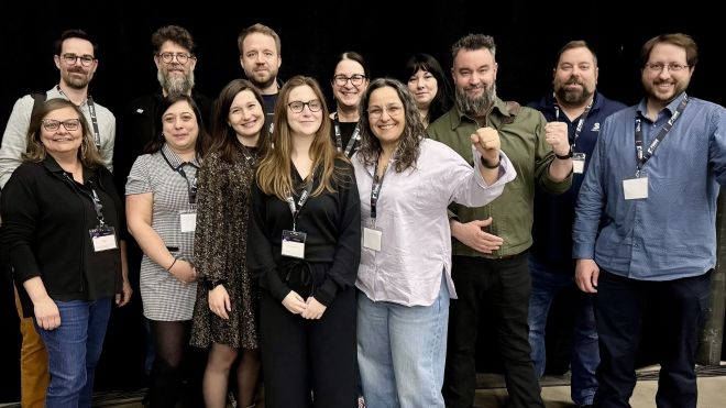 A large group in front of a black background, fists raised.