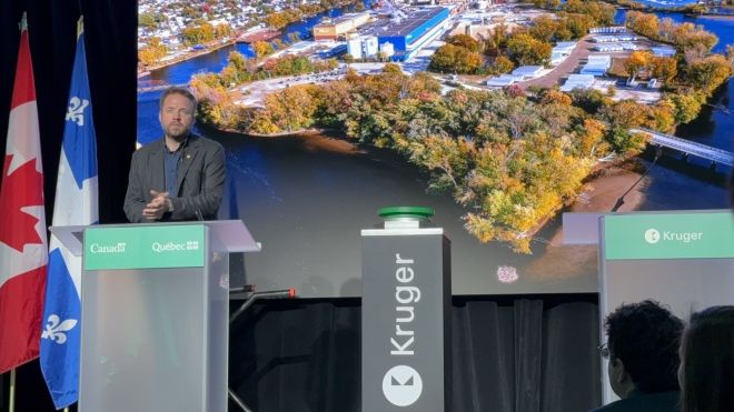 A man speaking at a podium in front of a screen