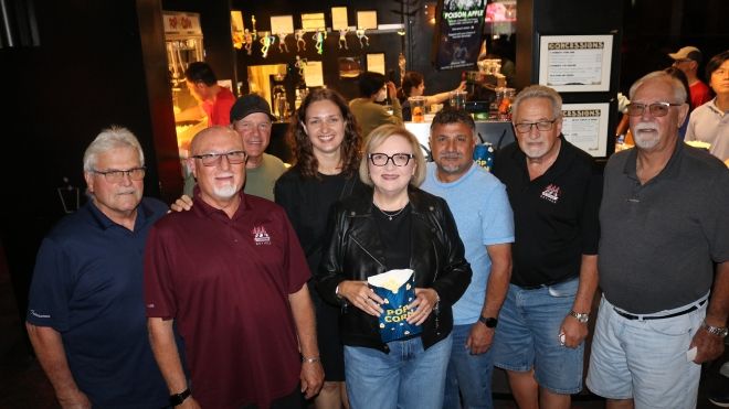 A group of people at a theatre a women in the middle holds a bag of popcorn