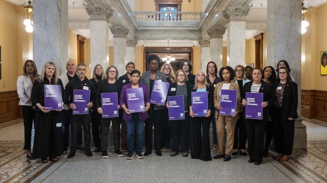 A large group of women holding purple IPV placards