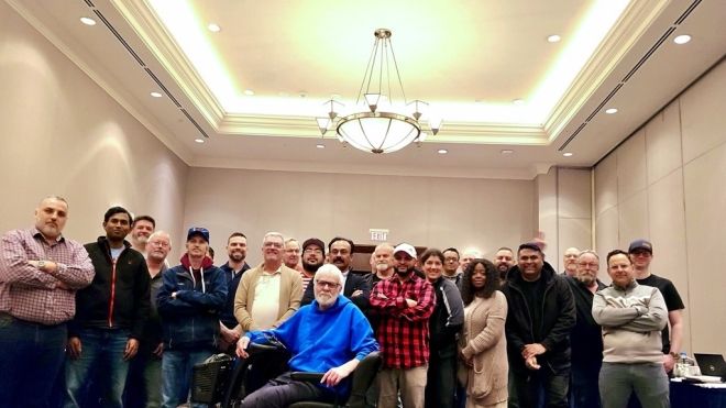 A large group posing in a hotel beige conference room