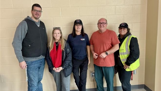 Five people posing by a beige wall