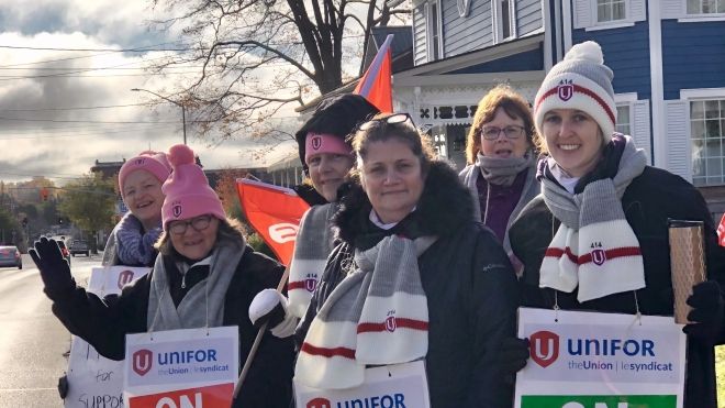 women holding signs on the pickline smiling.