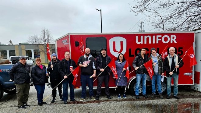A group of Unifor members standing in front of a Local 195 branded trailer.