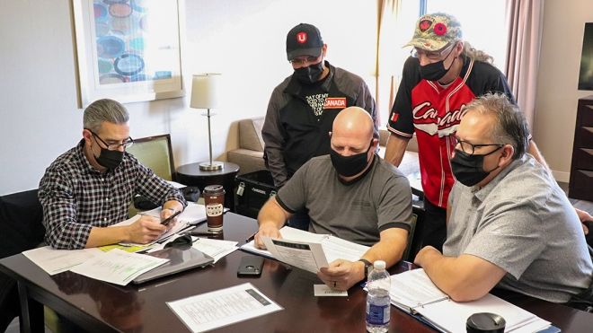 Five Unifor members in facemasks examining bargaining documents