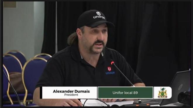 an image of a broadcast with a man sitting at a table speaking 