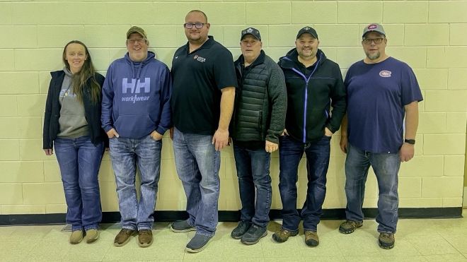 Six people smiling and posting for a photo indoors.