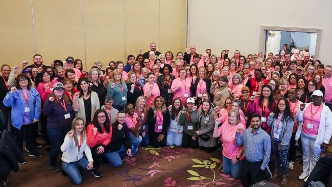 A very large group fists raised, some wearing pink shirts.