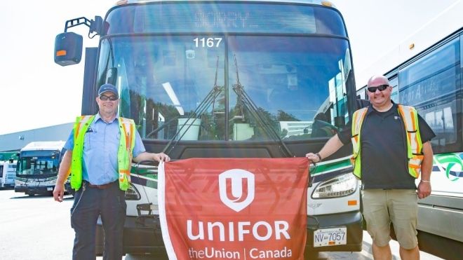 Two people holding a flag standing in front of a bus