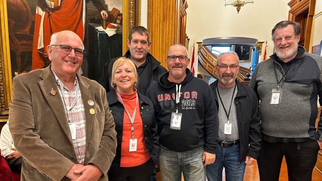 Unifor Atlantic Regional Director standing with a group of activists at the New Brunswick legislature.