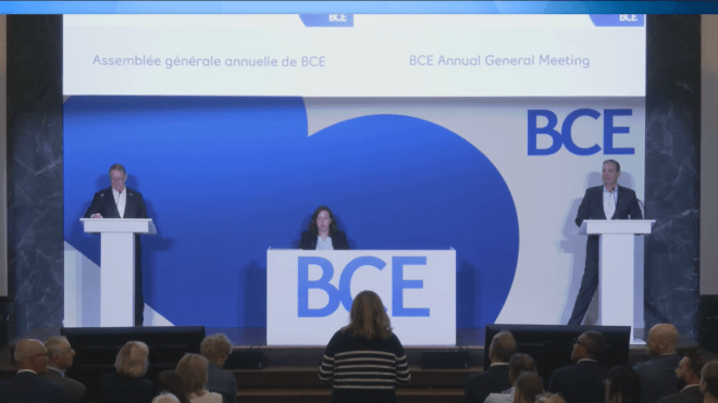 three people stand behind a Bell podium 