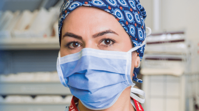 A nurse in scrubs with a mask on
