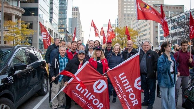 Membres du SCFP sur le piquet de grève tenant des drapeaux et des pancartes.