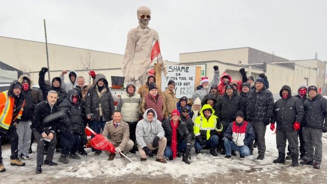 a large group of workers outside around a extra large skeleton