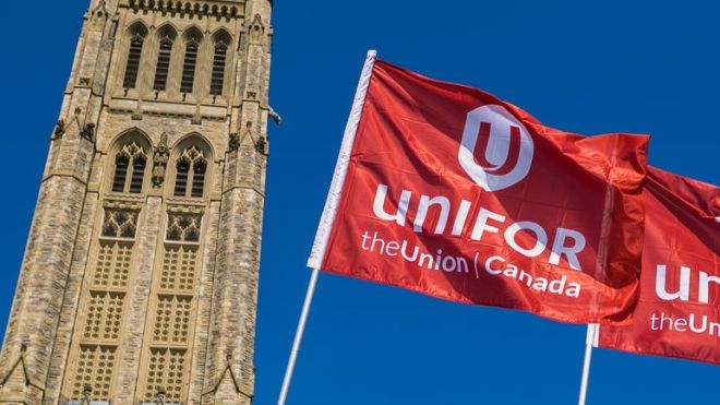 Two Unifor flags fly in front of the Peace Tower on Parliament Hill in Ottawa.