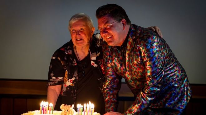 two men blowing out candles on a cake