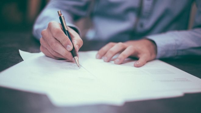 person writing on paper with a pen