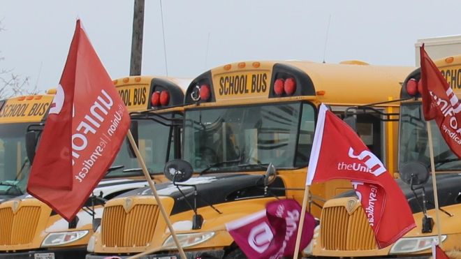 Parked school buses with Unifor flag in front 