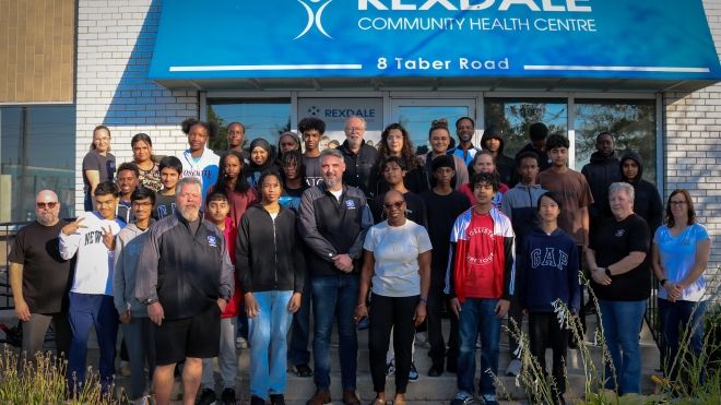 A group of students and teachers stand outside of a Rexdale Health Community centre