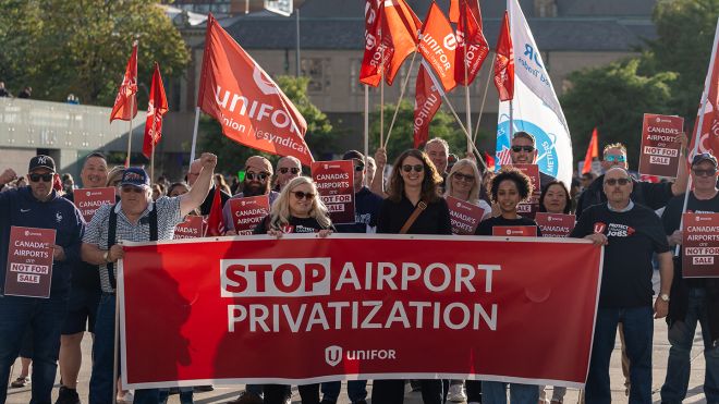 A group of people holding a red Unifor banner and flags