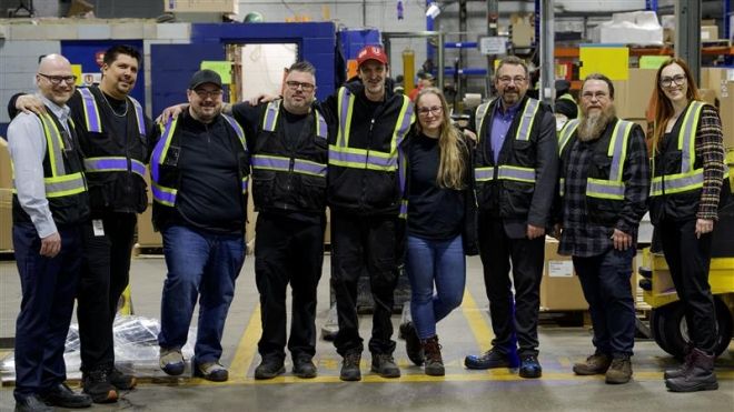 nine workers in dark safety uniforms proudly standing together smiling