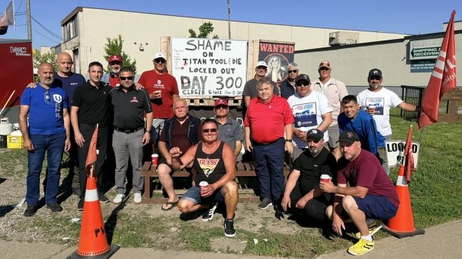 Titan Tool workers gathered outside of the plant around a sign that reads: Shame on Titan Tool locked out day 300.