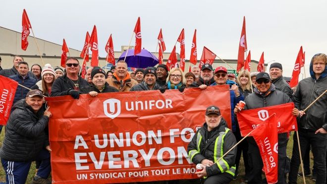 A large group standing behind a red Unifor banner that reads: A union for everyone