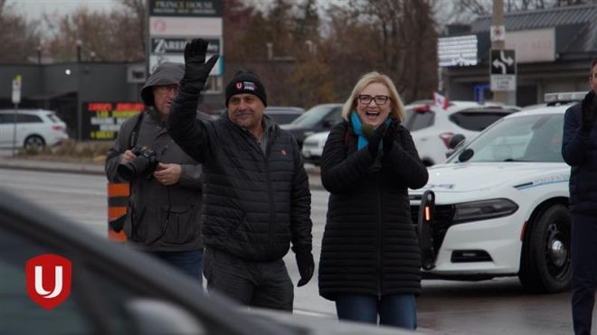 A women clapping and man waving around cars