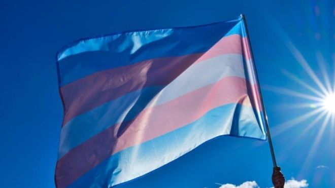 Transgender flag in a sunny blue sky.