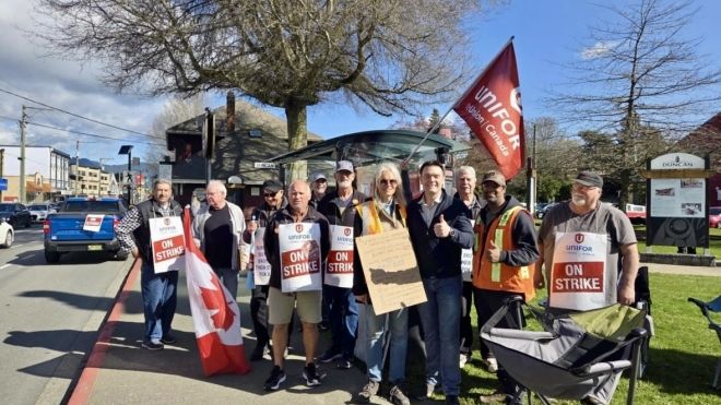 A group of people standing outside holding strike signs 