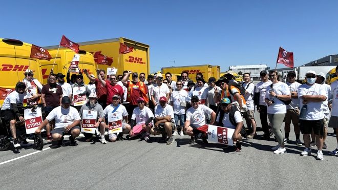A group of people with strike signs and DHL vans in the background.