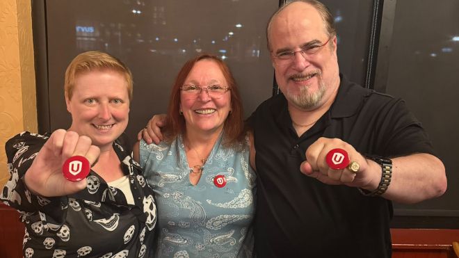 Three people smiling holding up red Unifor buttons