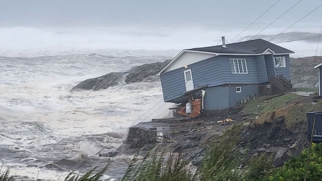 A house hangs over the coast of NL while waves crash on the shore