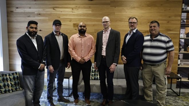 Six CPCK bargaining committee members posing in front of a wood plank wall
