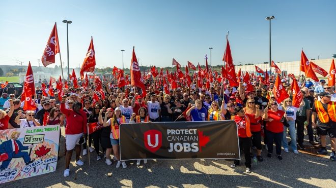 large group of people standing outside holding a Protect Canadian Jobs banner. 