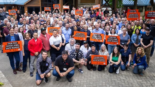 A group of people holding orange Safe Rates placards.