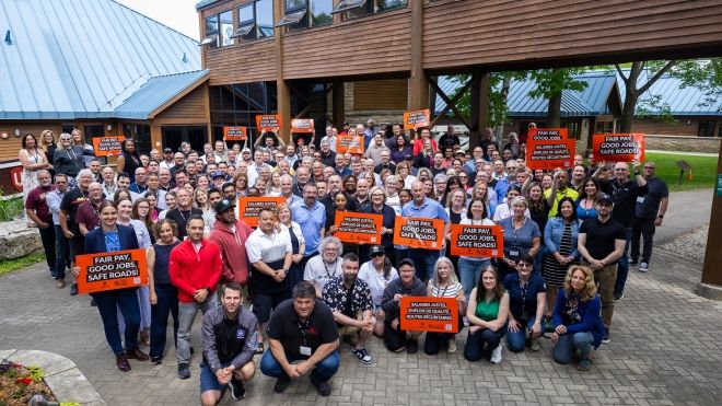 A group of people holding orange Safe Rates placards.