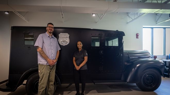 two people standing beside a Brinks truck