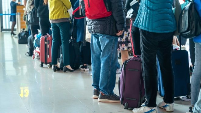 People standing in line with luggage at the airport check in.