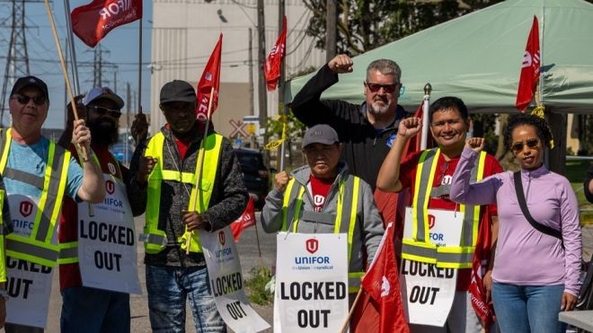 A group holding flgs and placcards wearing safety vests
