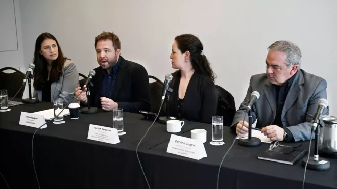 Four people sitting at mics behind a table