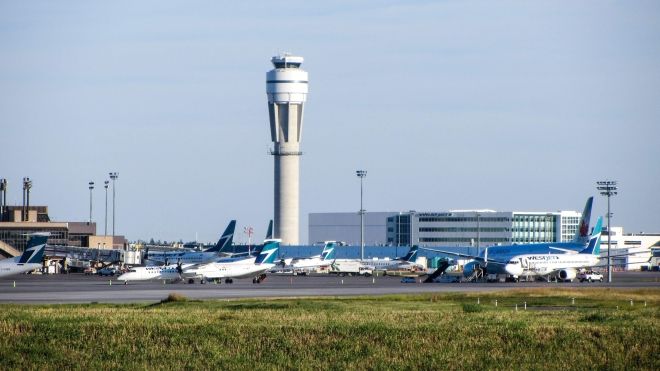 Airplanes on the tarmac with airport in the background.