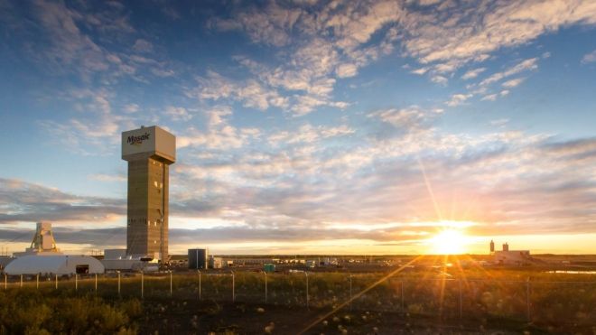 Landscape with a mining tower with a Mosaic logo in the foreground and a sunrise in the distance.